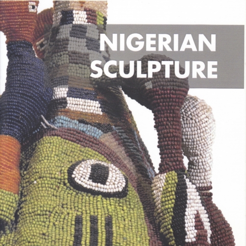 Exhibition catalogue cover, bearing a a cropped, zoomed in photograph of a Yoruba crown, comprised of colorful beads and fabric, the front of which bears the depiction of a green, beaded face. Superimposed on the top right of the cover is a band of grey, placed on top of which is the title of the catalogue in white, "NIGERIAN SCULPTURE".